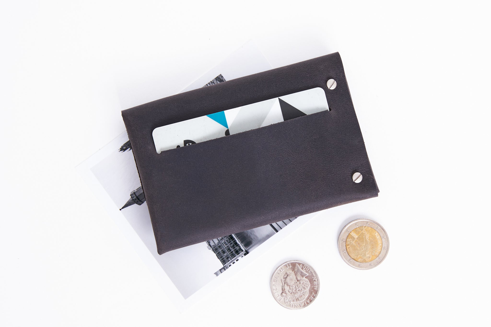 Minimalist leather wallet with slot for cards, coins and few folded bills.